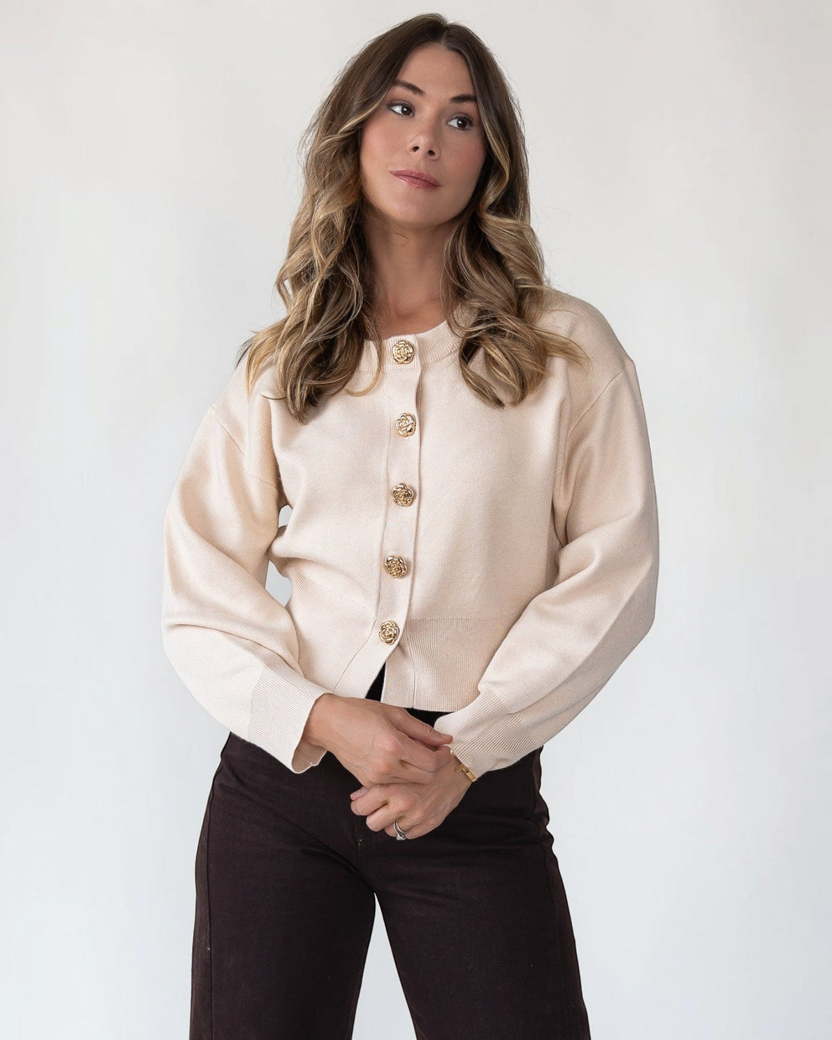Gold accent buttons set down the front of a cream cropped cardigan