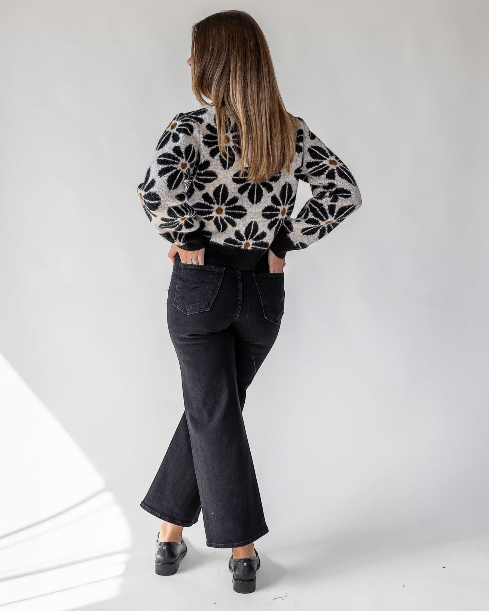 Cropped length hitting at the waist on a soft black cardigan