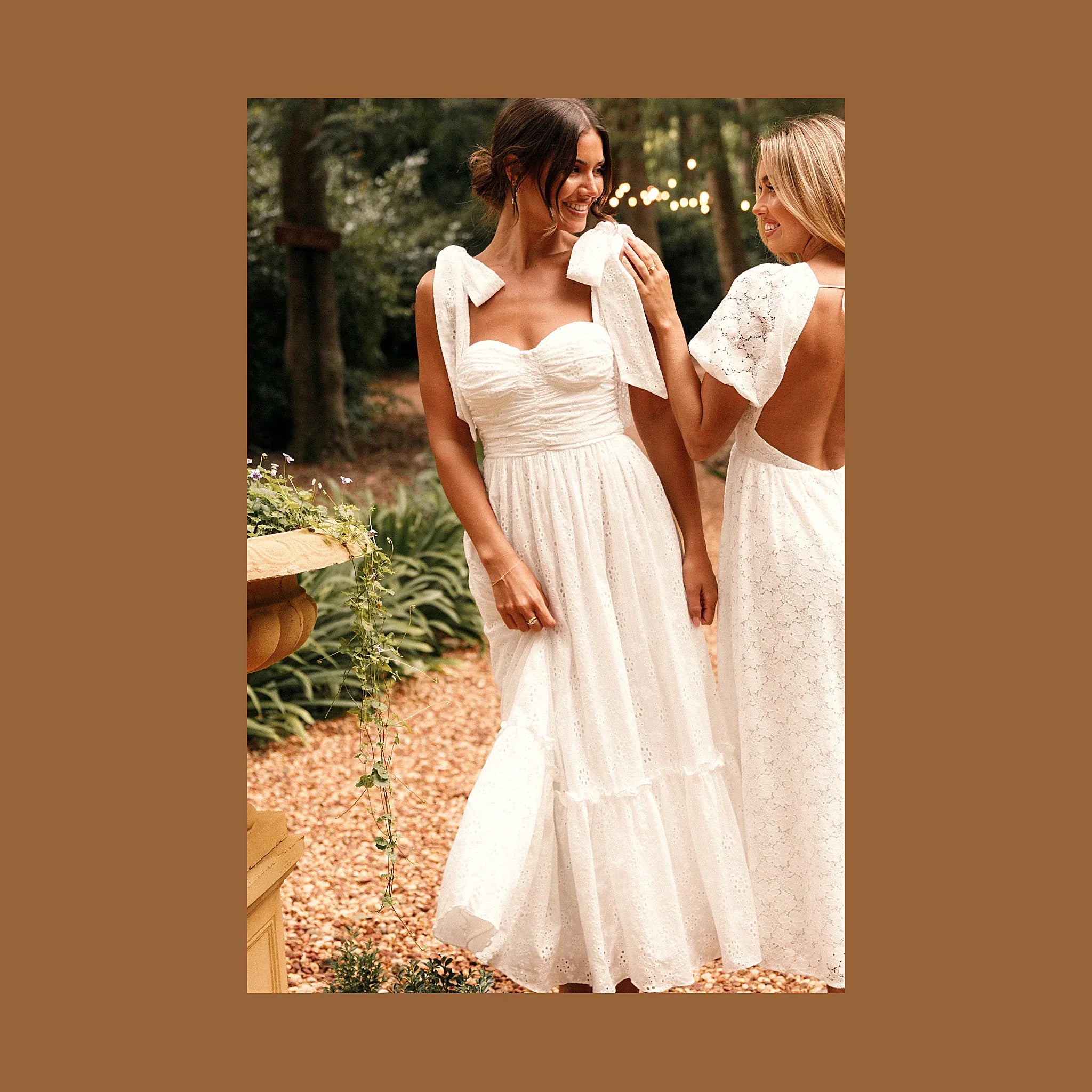 A white lace maxi dress with tie straps, worn outdoors.