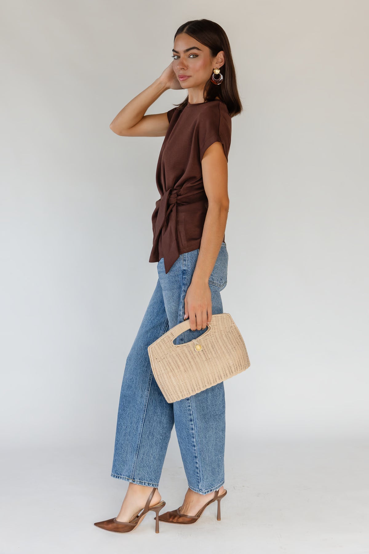 Side-tie knot detail cinching the waist of an unlined brown knit top