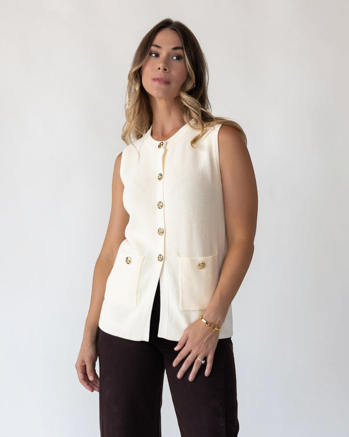 Vintage-inspired gold buttons down the front of a cream knit vest