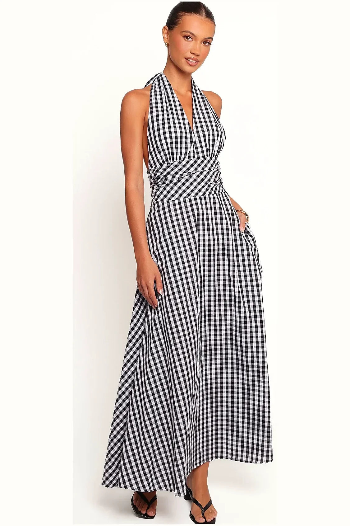 Model wearing a long gingham halter dress, side angle