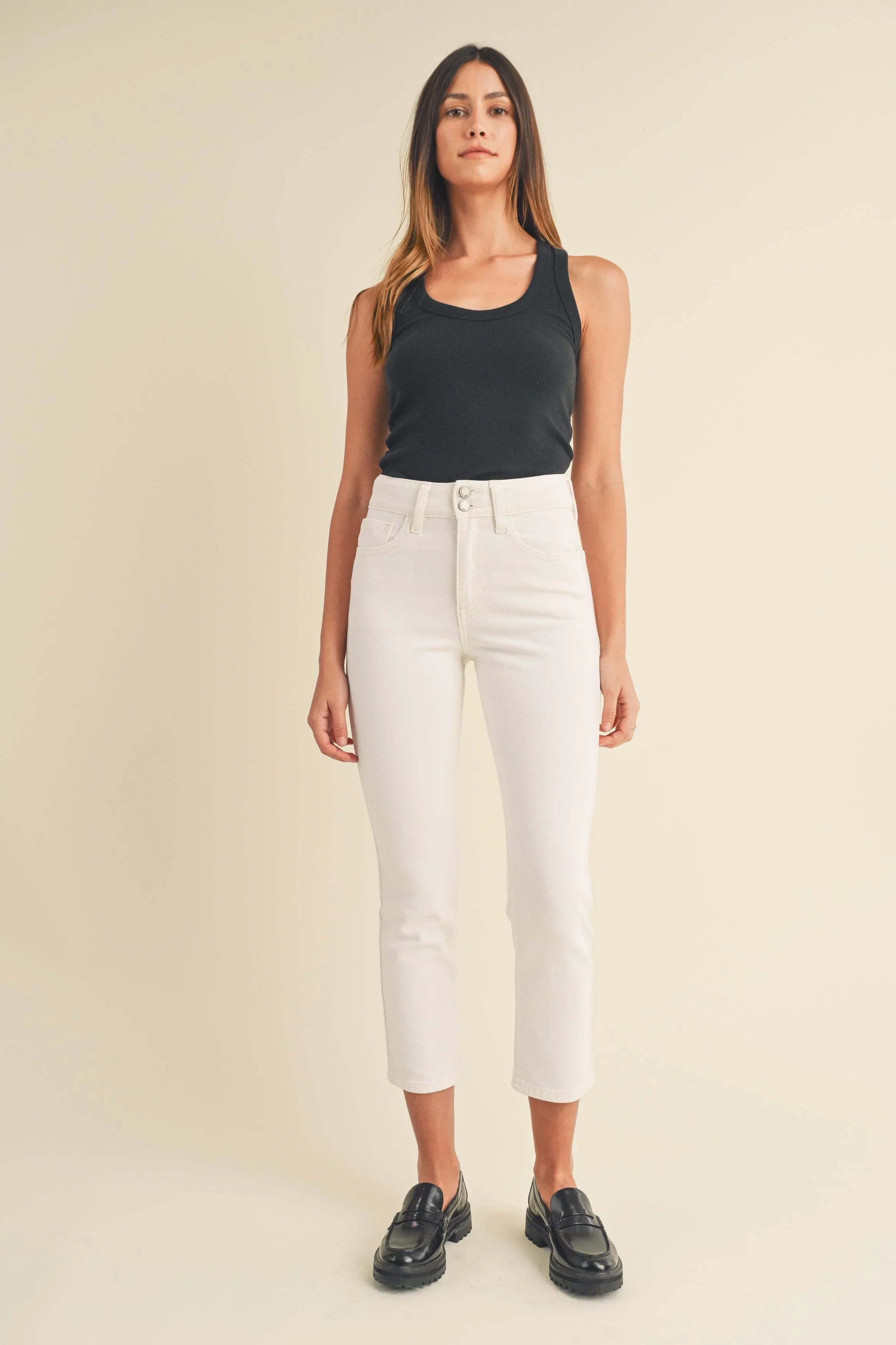 Double button closure at the waist of a white jean